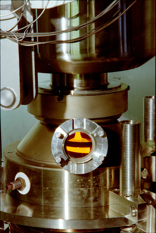 Sichtfenster mit Blick auf den Glasabstich der Pilotverglasungsanlage des Instituts für Nukleare Entsorgungstechnik am Forschungszentrum Karlsruhe (Versuch ohne radioaktives Material), 1998, Fotografie unbekannter Urheberschaft. KIT-Archiv 28028/10943.