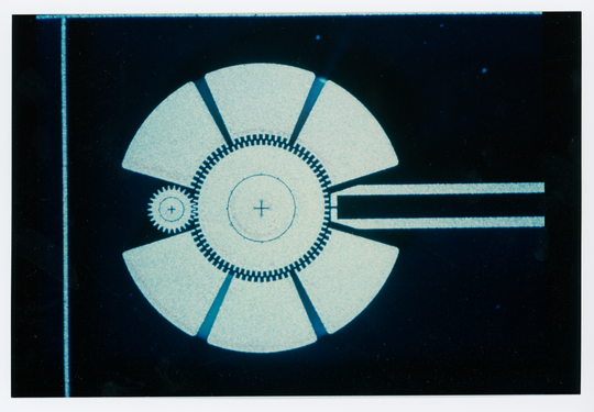 Rasterelektronenmikroskop-Aufnahme zweier Mikrozahnräder des Instituts für Mikrostrukturtechnik am Kernforschungszentrum Karlsruhe, 1990, Fotografie unbekannter Urheberschaft. KIT-Archiv 28028/19430.