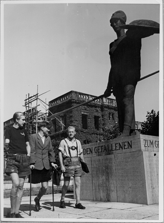 Kriegsversehrte im Ehrenhof der Technischen Hochschule Karlsruhe neben dem Denkmal für die Gefallenen des ersten Weltkriegs, im Hintergrund das zerstörte Chemische Institut, ca. 1947, Fotografie: Erich Bauer. KIT-Archiv 28010/I 3901.