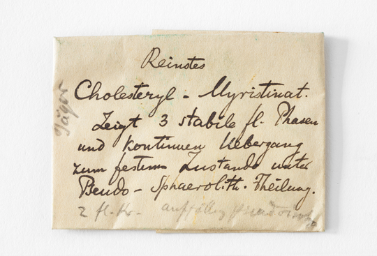 Papierumschlag mit der Substanz Cholesteryl-Myrist(in)at aus dem Nachlass von Otto Lehmann, ca. 1900. ca. 3,9 x 4,0 cm. KIT-Archiv 27059/88. Fotografie: Hubert Czech.